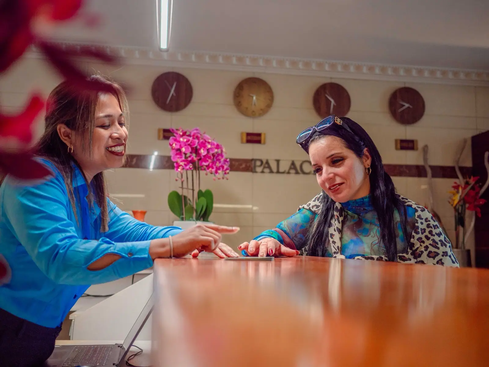 A front-desk staff member helping a guest at Hotel Palacio reception in Paramaribo